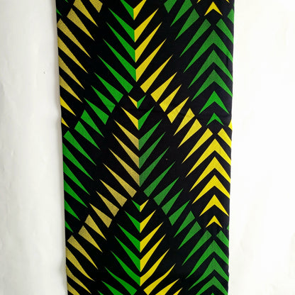 A vertical rectangular fabric featuring a bold geometric chevron pattern in black, green, and yellow, displayed against a plain white background.