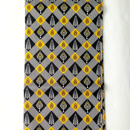A close-up of a patterned fabric or featuring a repeating geometric design in black, white, yellow, and grey.