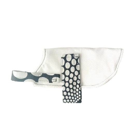 A white fabric cooling coat with a black strap featuring a white polka dot pattern, laid flat on a white background.