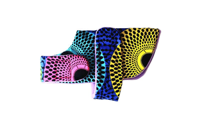 A dog coat with vibrant geometric patterns in pink, blue, yellow, and black, arranged on a plain white background.
