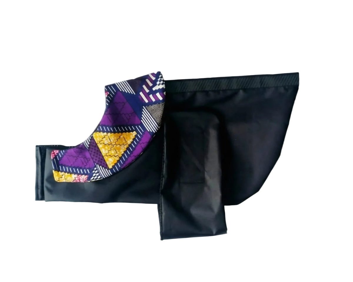 A black fabric dog raincoat with a colourful geometric patterned trim, laid flat on a white background.