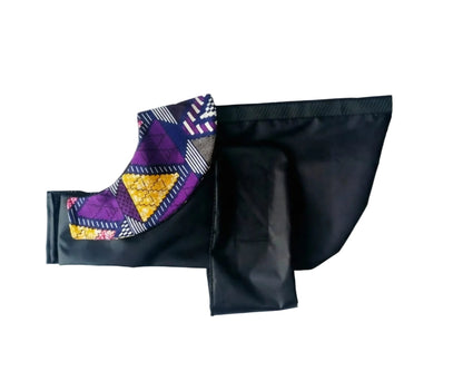 A black fabric dog raincoat with a colourful geometric patterned trim, laid flat on a white background.